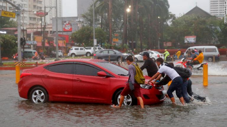水にはまった車を押す人たち＝１５日、マニラ/Bullit Marquez/AP