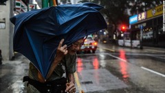 強風のなかタクシーを待つ男性＝１６日、香港