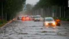 冠水した道路を進む車両＝１５日、マニラ