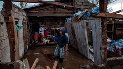 破損した住宅の調べる一家＝１５日、フィリピン