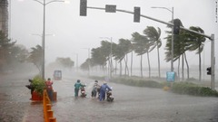 バイクを押して進む人々＝１５日、マニラ