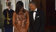 ヴェルサーチェのきらめくドレスを身にまとったミシェル・オバマ前米大統領夫人。隣にはオバマ前大統領の姿も