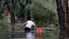 フロリダ州セントマークスの住民が自宅近くでクーラーボックスを引っぱる様子＝１０日