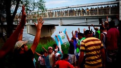 メキシコ国内に入った移民たちがゲート前で入国を待つ人たちに歓声を送った