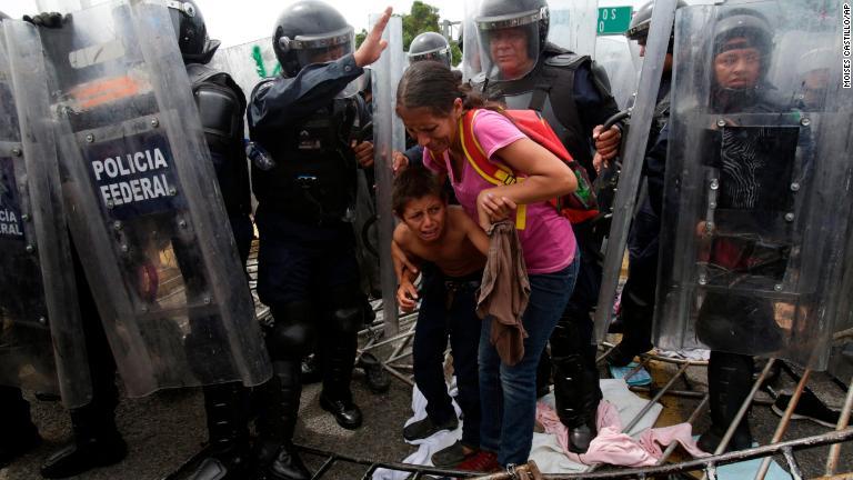 ホンジュラスの親子とメキシコ連邦警察の警官＝１９日/Moises Castillo/AP