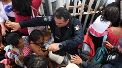 グアテマラとの国境で移民の親子を守るメキシコの係官＝１９日