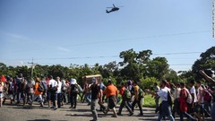 集団の上空を飛ぶメキシコ連邦警察のヘリコプター