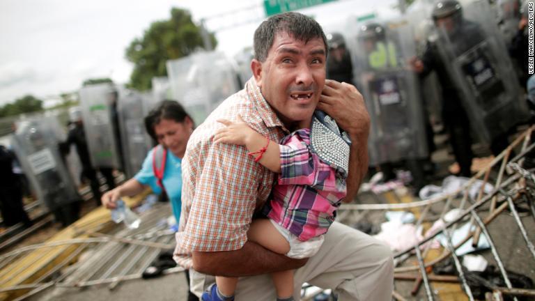 子どもを守るホンジュラスの男性。移民集団の一部が検問所を突破した＝１９日/Ueslei Marcelino/Reuters