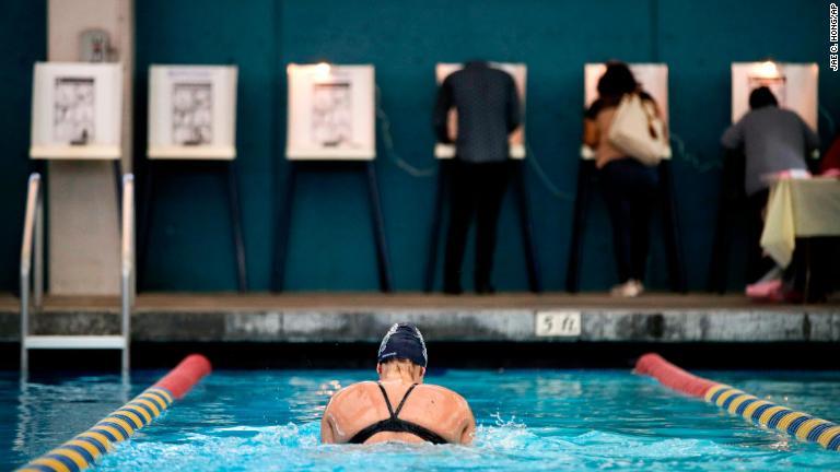投票する有権者の近くで泳ぐ女性＝ロサンゼルス/Jae C. Hong/AP
