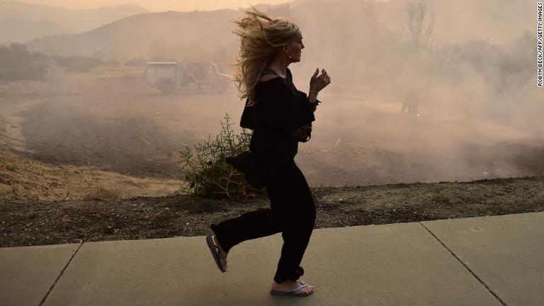 消防隊員が消火作業に当たるなか、避難する女性＝１０日、カリフォルニア州カラバサス/Robyn Beck/AFP/Getty Images
