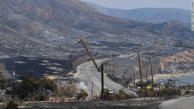 火災によって焼け落ちた山腹と傾いた電柱＝１０日、カリフォルニア州マリブ近郊/Robyn Beck/AFP/Getty Images