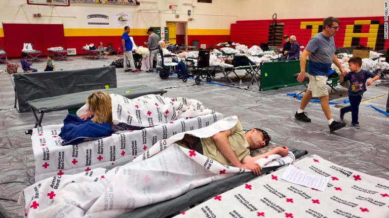 高校の体育館で休む避難してきた人たち＝９日、ロサンゼルス/Richard Vogel/AP