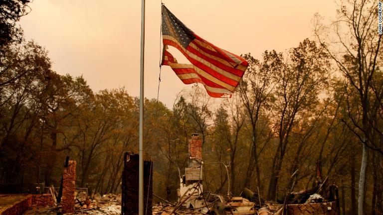 焼け落ちた家屋の横ではためく星条旗＝１１日、カリフォルニア州パラダイス/John Locher/AP