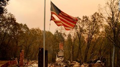 焼け落ちた家屋の横ではためく星条旗＝１１日、カリフォルニア州パラダイス