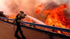高速道路から放水する消防隊員＝１２日、カリフォルニア州シミバレー