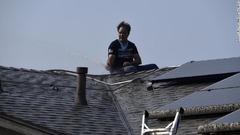 自宅の屋根を水で洗い流す男性＝１２日、カリフォルニア州シミバレー