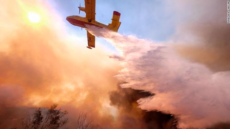 上空から水をまく航空機＝１２日、カリフォルニア州シミバレー/Ringo H.W. Chiu/AP