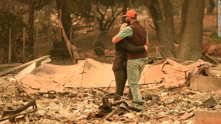 自宅の残骸で抱き合う夫婦＝１２日/JOSH EDELSON/AFP/Getty Images