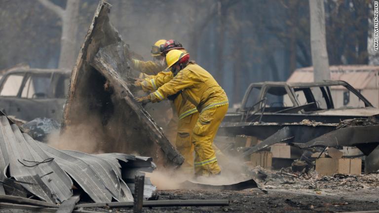 損壊した家屋で捜索を行う消防隊員＝１３日、パラダイス/Terry Sylvester/Reuters