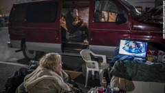 駐車場でテレビを見る避難者＝１５日