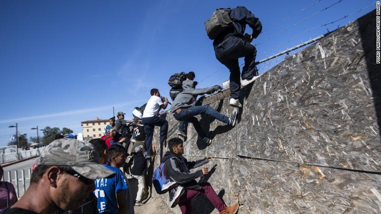 米・メキシコ国境へ向かおうとフェンスを乗り越える人々/Pedro Pardo/AFP/Getty Images