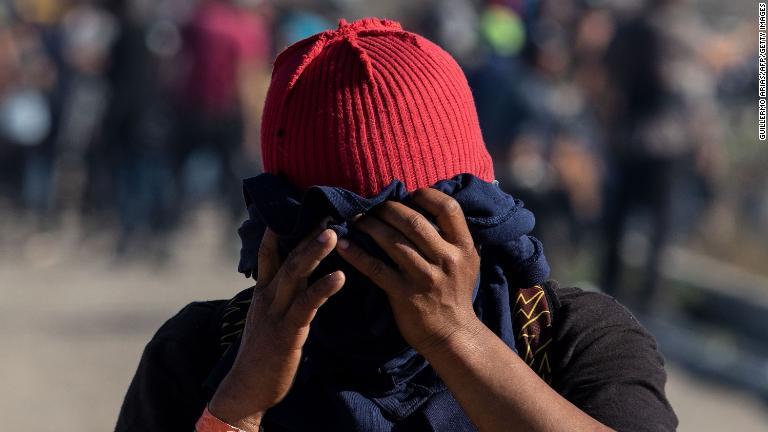 催涙ガスが発射されたことを受けて、顔を布で覆う移民/Guillermo Arias/AFP/Getty Images