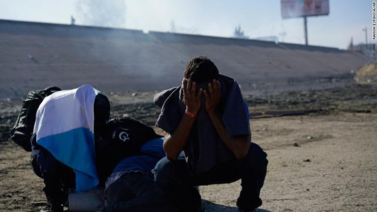催涙ガスのために顔を覆う男性/Ramon Espinosa/AP