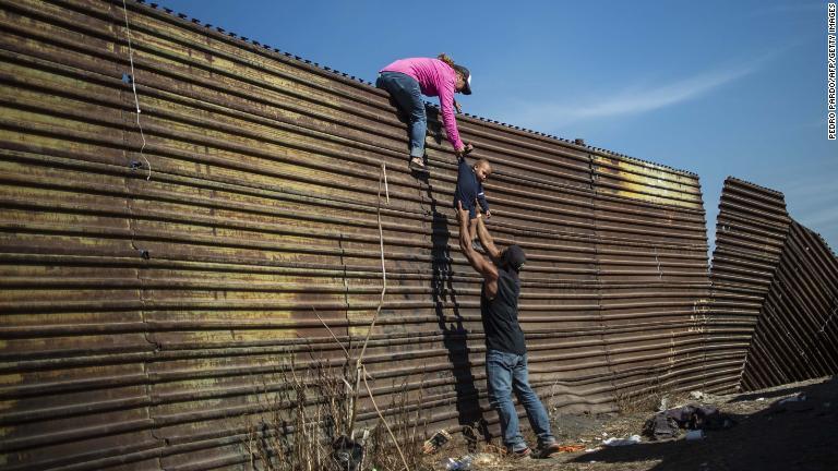 検問所を通過できなかった移民は、古いフェンスをよじ登って越境しようとする/Pedro Pardo/AFP/Getty Images