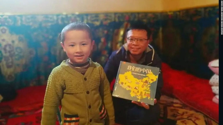 「私たちの中国」という絵本をウイグル族の子どもに贈る職員の男性。男性はこの家族の「親戚」として位置付けられる/Xinjiang Chinese Communist Youth League