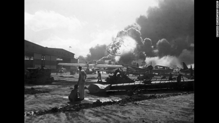 爆弾が爆発する様子を見るヒッカム空軍基地の空軍隊員。同基地は日本軍爆撃機による重点的な攻撃対象となり、地上にあった米軍機を無効化することで米軍からの反撃を防ごうとしていた/Bettmann Archive/Getty Images