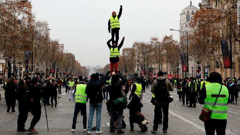 「人間タワー」を作るデモ参加者＝１５日、パリのシャンゼリゼ通り/Kamil Zihnioglu/AP