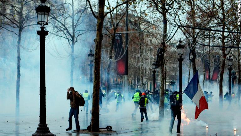 催涙ガスからの逃れようとするデモ参加者＝１５日、パリ/Kamil Zihnioglu/AP