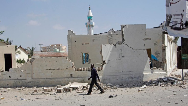 爆発によって破損した建物の横を歩く男性＝２２日、モガディシオ/Farah Abdi Warsameh/AP