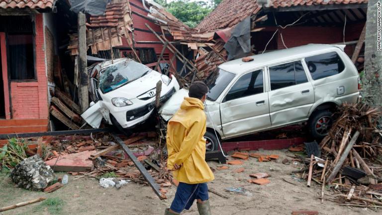 津波で損壊した車両の横を歩く住民＝インドネシア・カリタ/Dian Triyuli Handoko/AP
