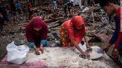 破損した家屋から米を回収する女性たち＝インドネシア・カリタ