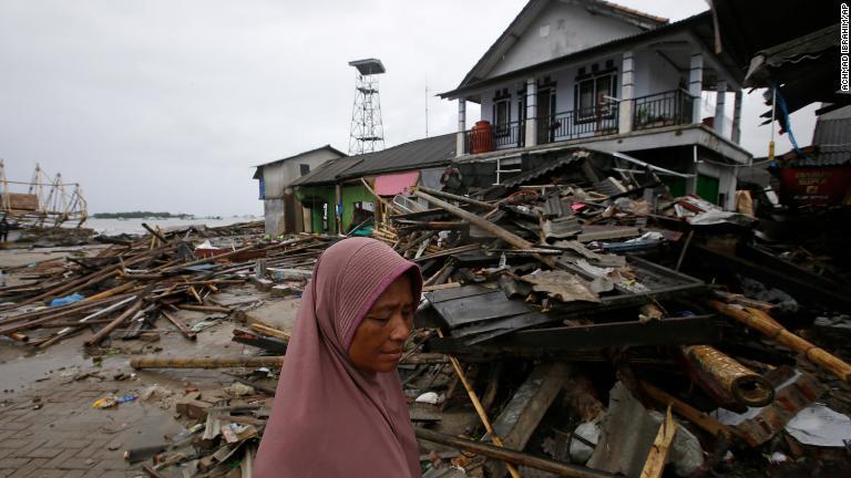 被災地を歩く女性＝２５日/Achmad Ibrahim/AP