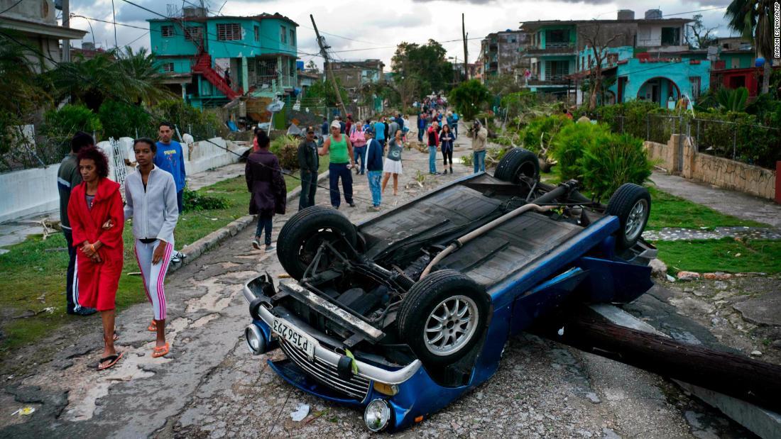 ひっくり返った車両の横を歩く人々/Ramon Espinosa/AP