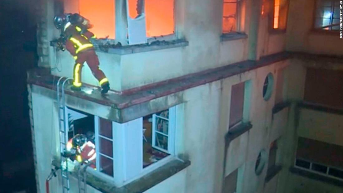 火災の起きた建物によじ登る消防隊員/Paris Fire Department via AP