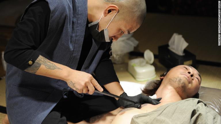 彫り師の彫妙氏が書道家の鈴木隼人氏の肩に刺青を施している/YOSHIKAZU TSUNO/AFP/AFP/Getty Images