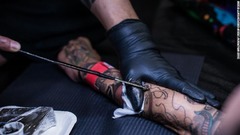 香港国際タトゥーコンベンションで女性が手彫り刺青の施術を受ける様子