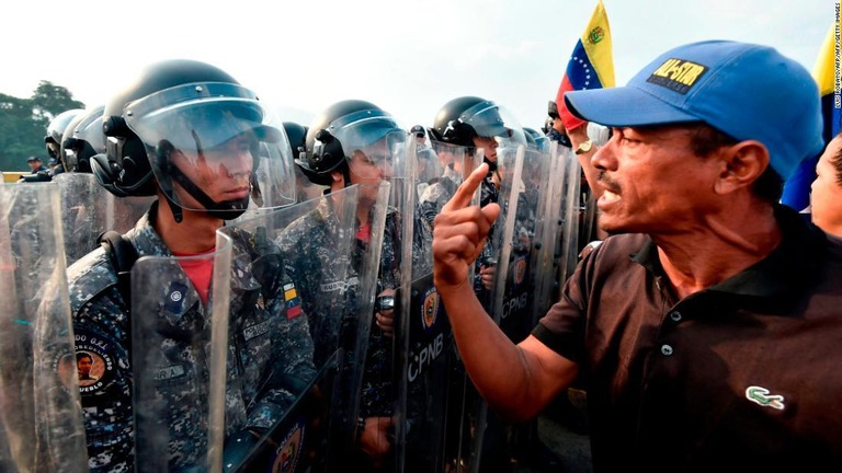 警官隊の前で、国際社会からの救援物資の搬入を求める男性/LUIS ROBAYO/AFP/AFP/Getty Images