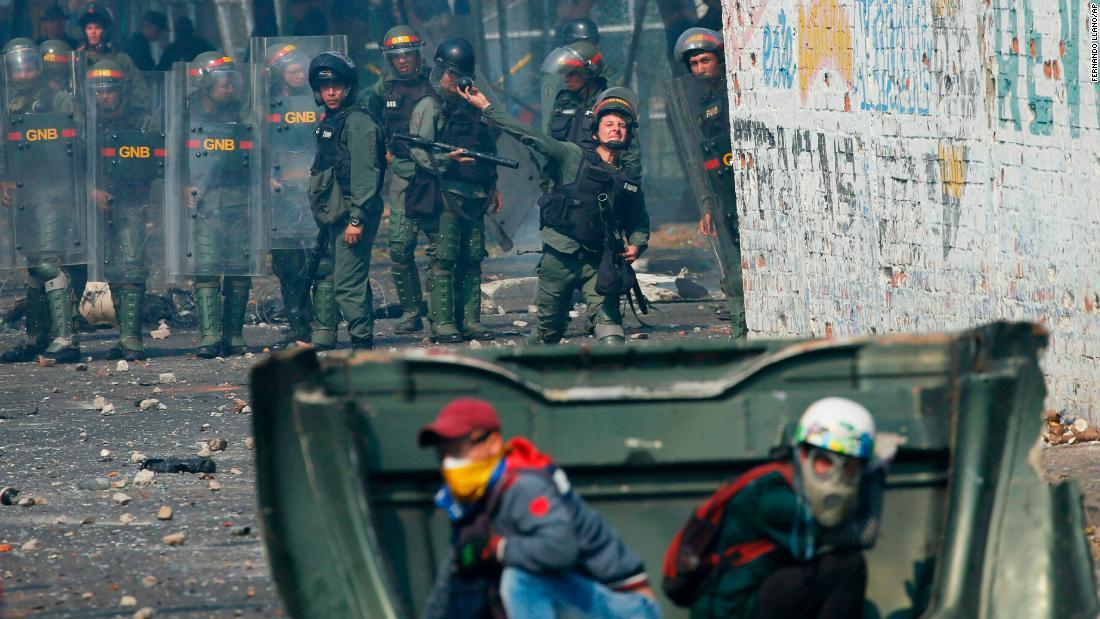 デモ隊に向けて催涙ガス弾を投げる治安部隊/Fernando Llano/AP