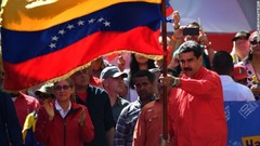 政権支持派によるデモ行進で国旗を掲げるマドゥロ大統領＝２３日、首都カラカス