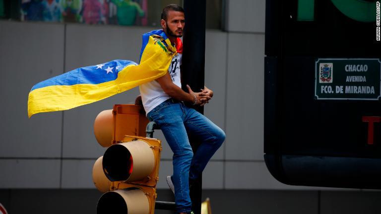 ベネズエラ国旗を身にまとった男性/Ariana Cubillos/AP