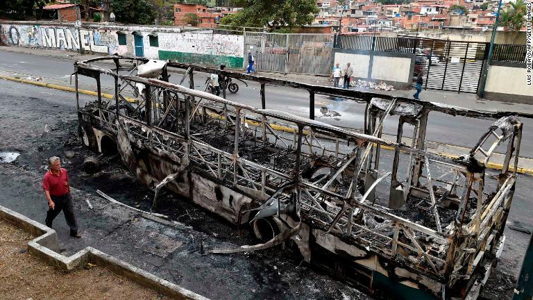 焼かれたバスの横を歩く男性＝首都カラカス/Luis Robayo/AFP/Getty Images