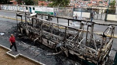 焼かれたバスの横を歩く男性＝首都カラカス
