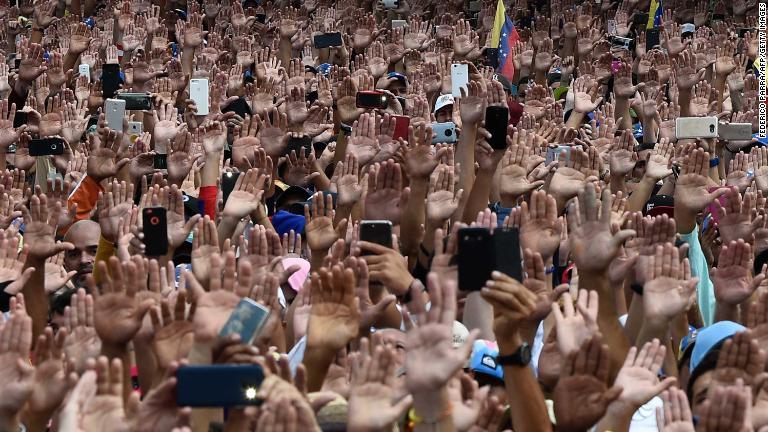 手をあげてグアイド氏との団結を示すデモ参加者/Federico Parra/AFP/Getty Images