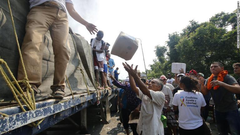 出火した車両から支援物資を運び出す人々＝２３日/Schneyder Mendoza/AFP/Getty Images