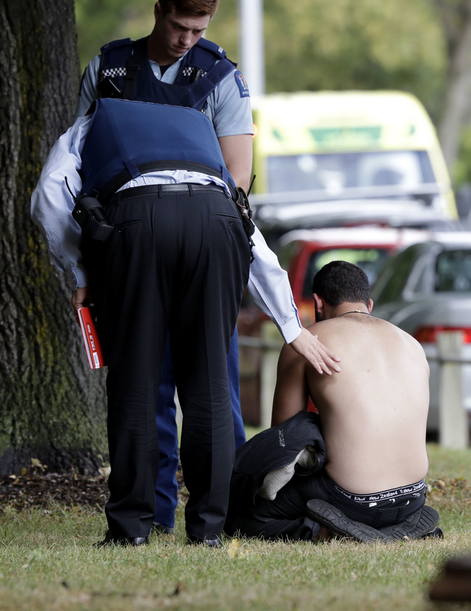 モスク付近で男性を慰める警察官/Mark Baker/AP