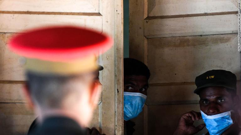 遺体安置所のドア付近に立つ病院職員や兵士/Lakruwan WanniarachichiGetty Images